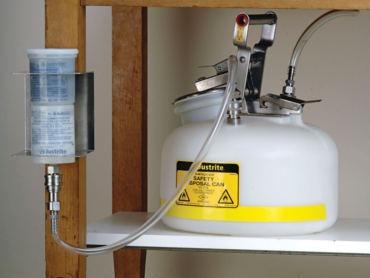 Justrite white HPLC hazardous waste container with carbon filter mounted on workstation with filter wall bracket